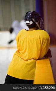 Rear view of an ice hockey player leaning on a railing