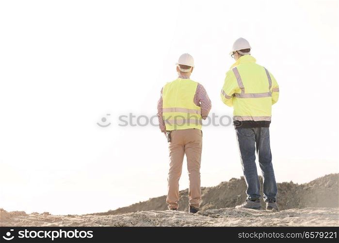 Rear view of architects standing at construction site against clear sky