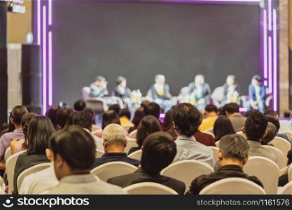 Rear view of Asian audience joining and listening group of speaker talking on the stage in the seminar meeting room or conference hall, business and education, associate and startup business concept