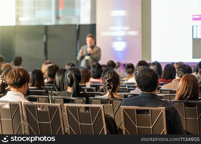 Rear view of Audience in the conference hall or seminar meeting which have speaker in front of the room on the stage, business and education concept