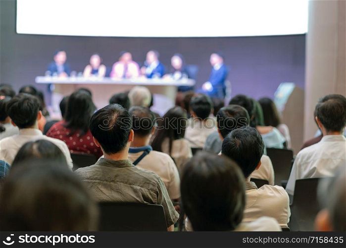 Rear view of Audience in the conference hall or seminar meeting which have Speakers are Brainstorming and talking on the stage, business and education about investment concept