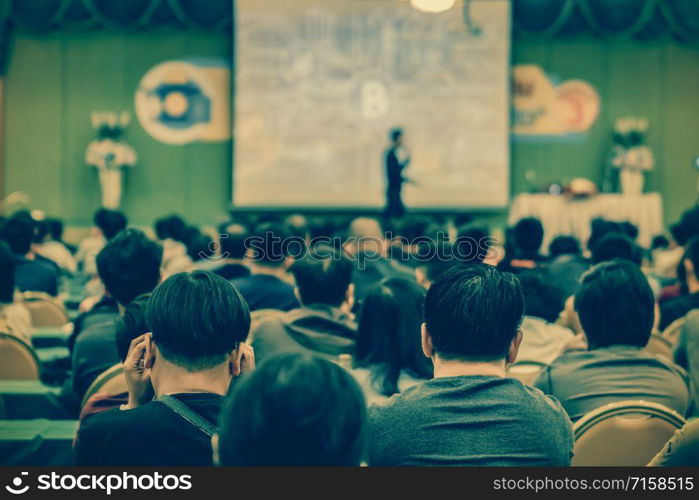 Rear view of Audience listening the speakers present the slide on the stage in the conference hall or seminar meeting, business and education concept