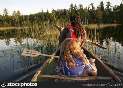 Rear view of blond girl and Africian American man rowing in a canoe at Lake of the Woods, Ontario