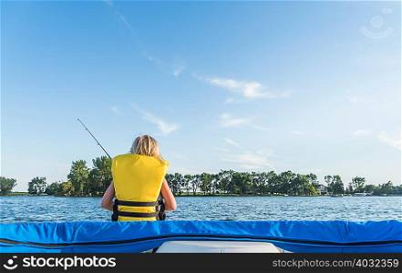 Rear view of boy wearing life jacket fishing