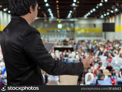 Rear view of Business People Conference Speaker on over the Abstract blurred photo of conference hall or seminar room which have Speakers on the stage with attendee background, business seminar and education concept