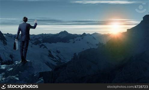 Rear view of businessman look at sunrise above mountain. Facing new day