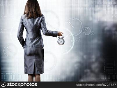 Rear view of businesswoman holding alarm clock in hand