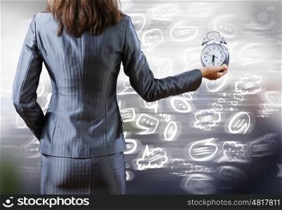 Rear view of businesswoman holding alarm clock in hand