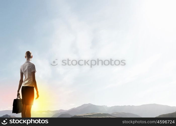 Rear view of businesswoman look at sunrise above mountain. Facing new day