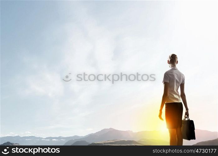 Rear view of businesswoman look at sunrise above mountain. Facing new day