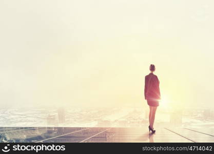 Rear view of businesswoman looking at sunset above city. New day