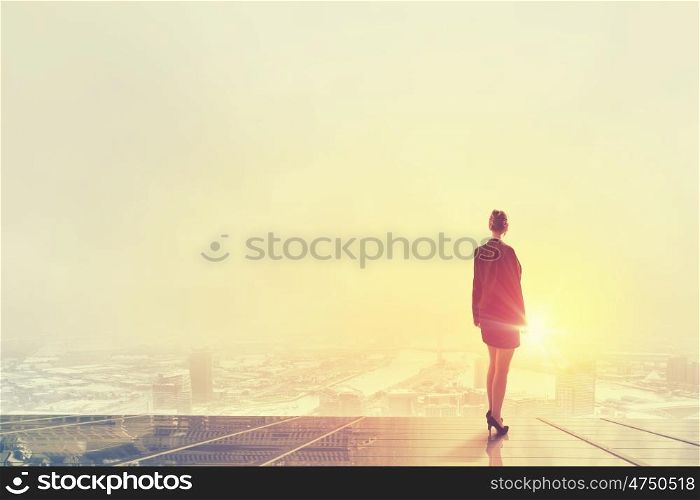 Rear view of businesswoman looking at sunset above city. New day
