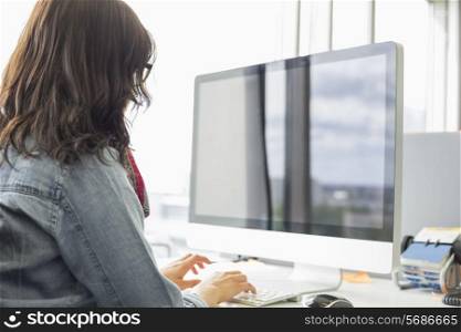 Rear view of businesswoman using desktop computer in creative office