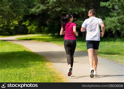 Rear view of Caucasian female and male runners outdoors