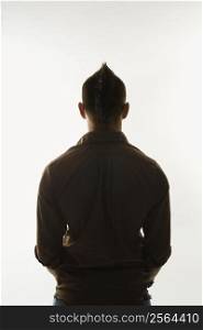 Rear view of Caucasian man with mohawk standing against white background.
