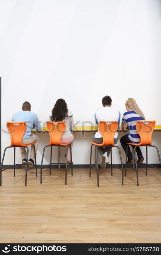 Rear View Of College Students Working At Desk Together