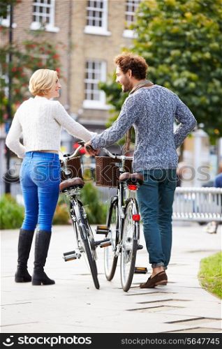 Rear View Of Couple Cycling Through Urban Park Together