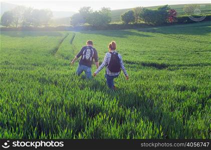 Rear view of couple hiking in field