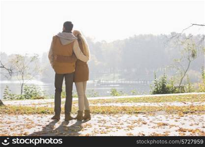 Rear view of couple looking at lake in park during autumn