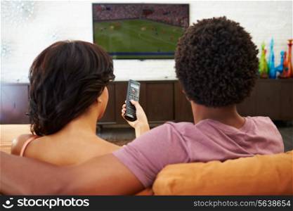 Rear View Of Couple Sitting On Sofa Watching TV Together