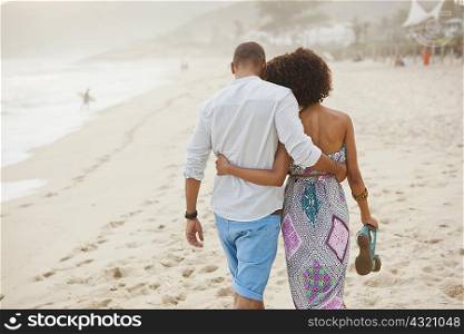 Rear view of couple strolling on beach, Rio De Janeiro, Brazil