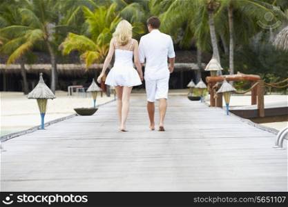 Rear View Of Couple Walking On Wooden Jetty