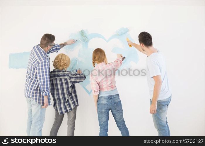Rear view of couples painting wall in new home