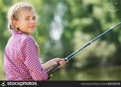 Rear view of cute girl sitting at bank and fishing