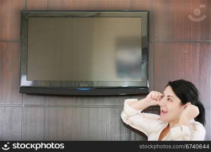Rear view of excited soccer fan standing up and watching favorite team goal at tv