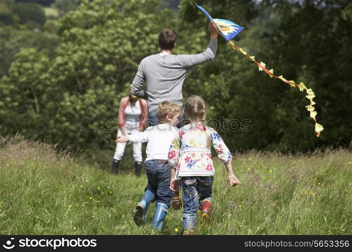 Rear View Of Family Flying Kite In Countryside