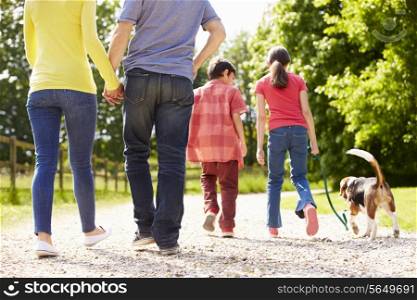 Rear View Of Family Taking Dog For Walk In Countryside