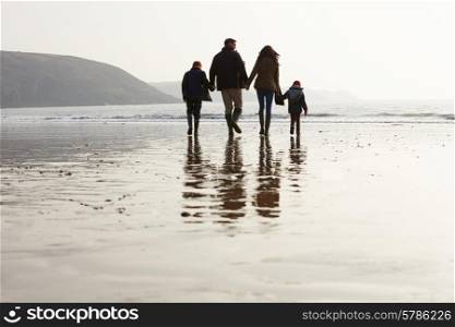 Rear View Of Family Walking Along Winter Beach