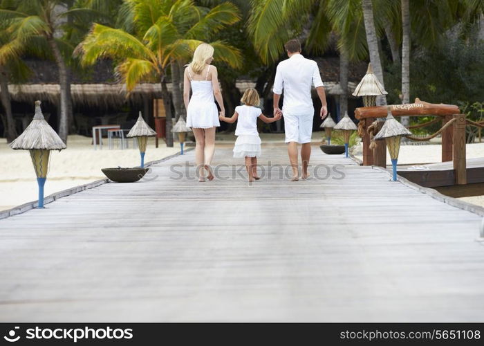 Rear View Of Family Walking On Wooden Jetty