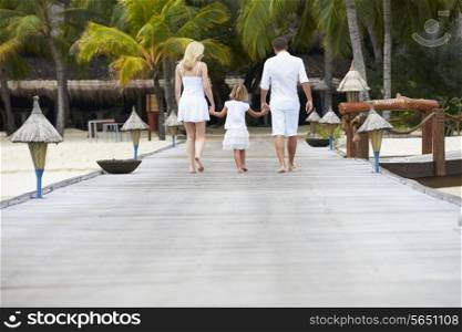 Rear View Of Family Walking On Wooden Jetty