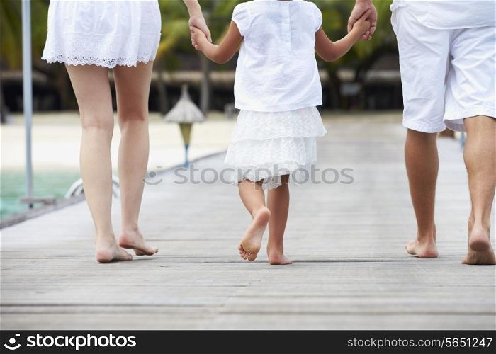Rear View Of Family Walking On Wooden Jetty
