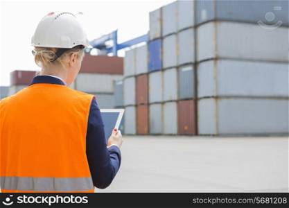 Rear view of female engineer using digital tablet in shipping yard