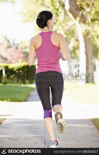 Rear View Of Female Runner Exercising On Suburban Street