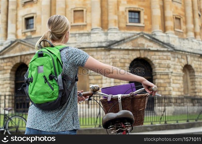 Rear View Of Female Student Riding Old Fashioned Bicycle Around Oxford University College Buildings By Radcliffe Camera In Radcliffe Square UK