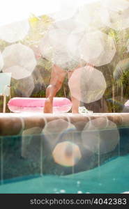 Rear view of female toddler toddling on sunlit poolside