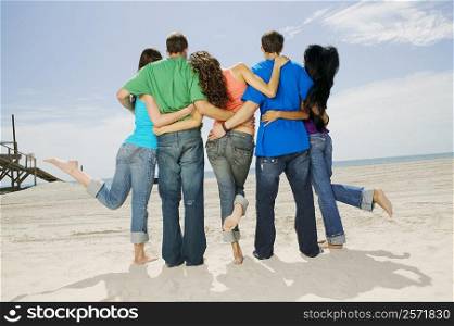 Rear view of five people standing on the beach