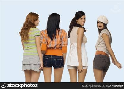 Rear view of four young women standing side by side