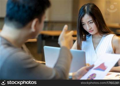 Rear view of Furious boss scolding Asian young businesswoman in casual suit by point to her face about performance and KPI in modern office, Business mistake and punish concept