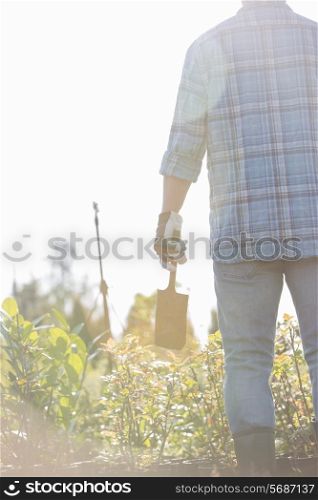 Rear view of gardener holding shovel at plant nursery
