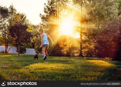 Rear view of girl in park running with Boston terrier puppy