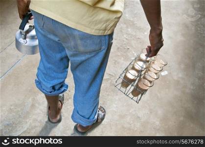 Rear view of Indian street seller with tray milk tea and kettle