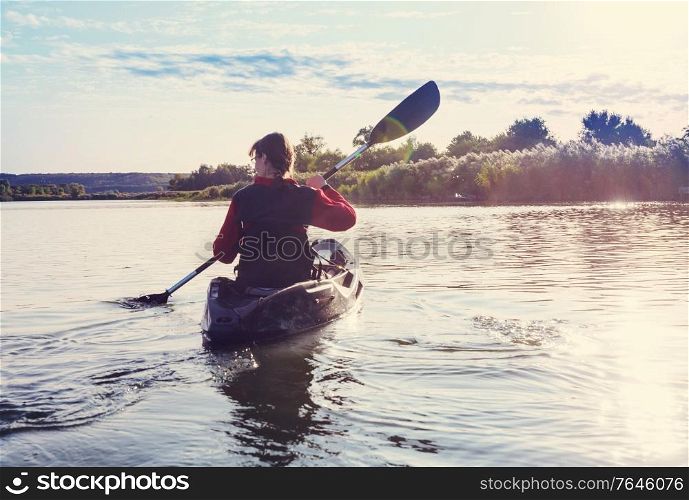 Rear view of kayaker paddle kayak in summer river