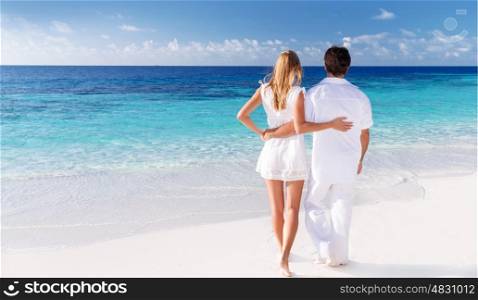 Rear view of loving couple enjoying seascape, active lifestyle, romantic feelings, honeymoon on luxury beach resort, summer vacation concept
