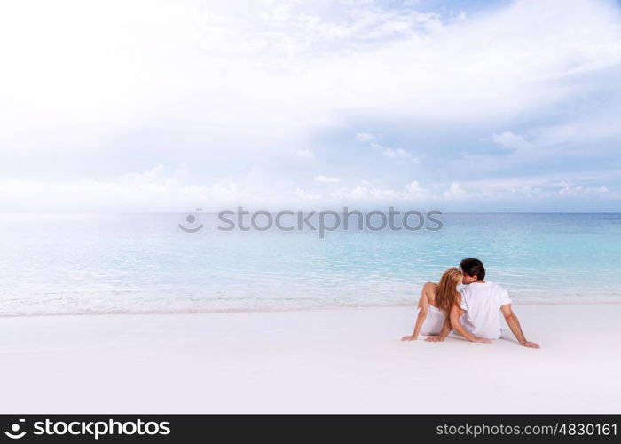 Rear view of loving couple relaxing on the beach, kissing outdoors, boyfriend with girlfriend enjoying summer holidays on luxury Maldives resort, love and romance concept&#xA;