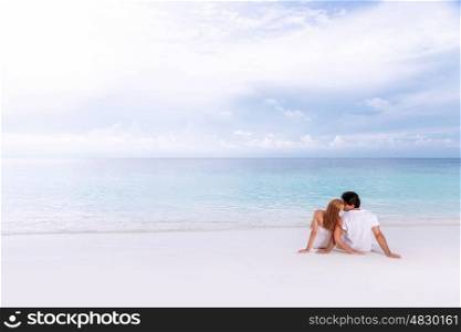 Rear view of loving couple relaxing on the beach, kissing outdoors, boyfriend with girlfriend enjoying summer holidays on luxury Maldives resort, love and romance concept&#xA;