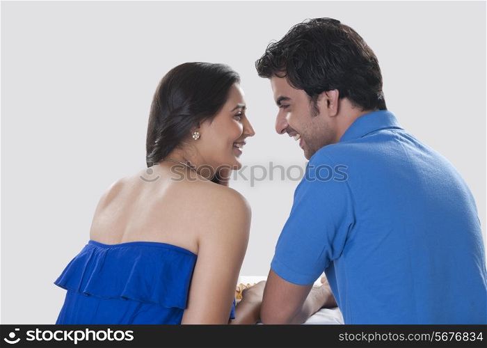 Rear view of loving young couple looking at each other against white background